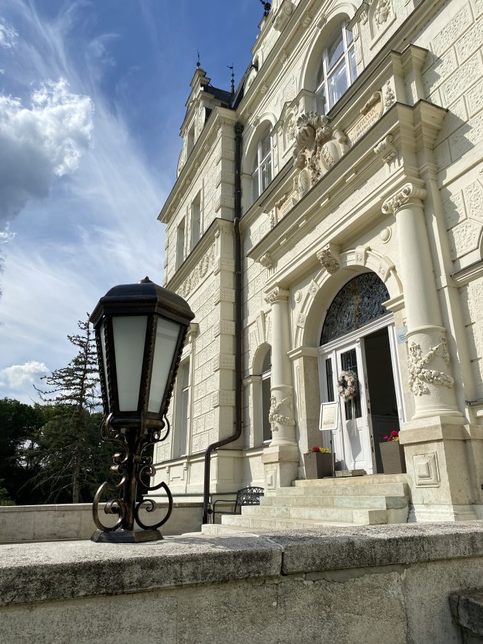 Historická budova s lampou, oblúkovým vchodom a detailnými ornamentmi.